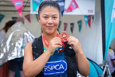 An event finisher holding up medal after race finished.
