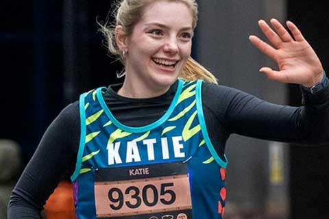 A smiling RSPCA fundraiser waving at an organised running event.