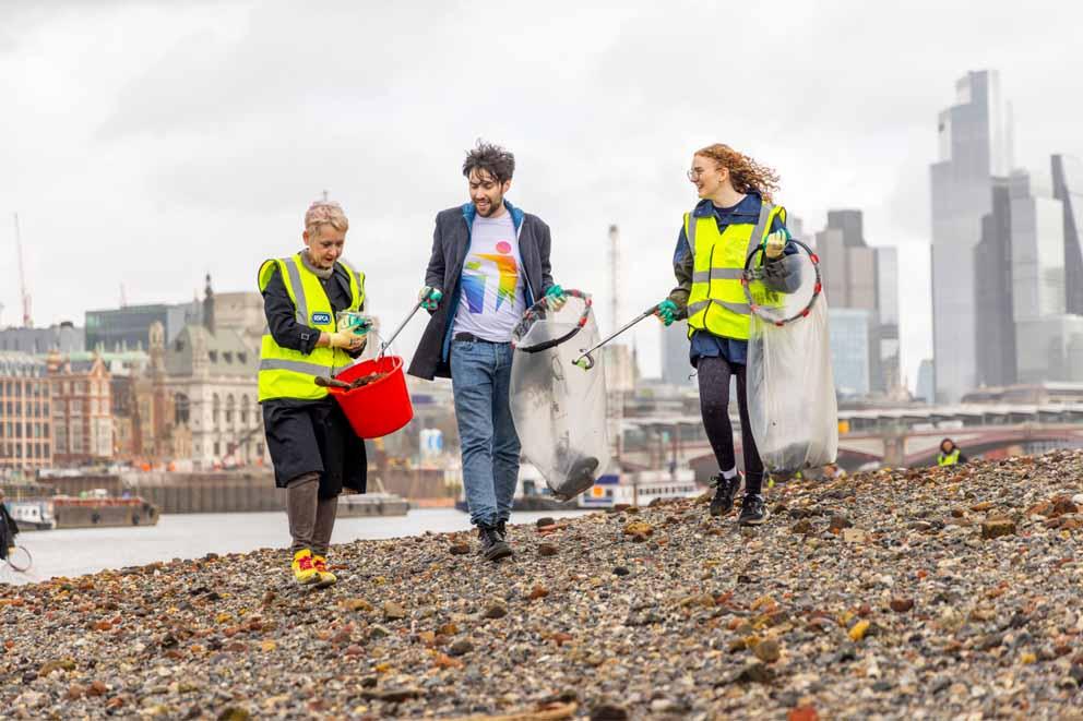 Three volunteer litter pickers on the banks of the river Thames in London.